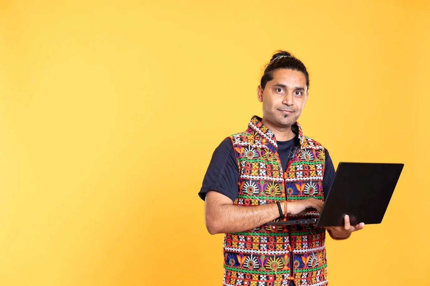 Porträt eines lächelnden Mannes, der am Laptop geschäftliche Aufgaben erledigt.