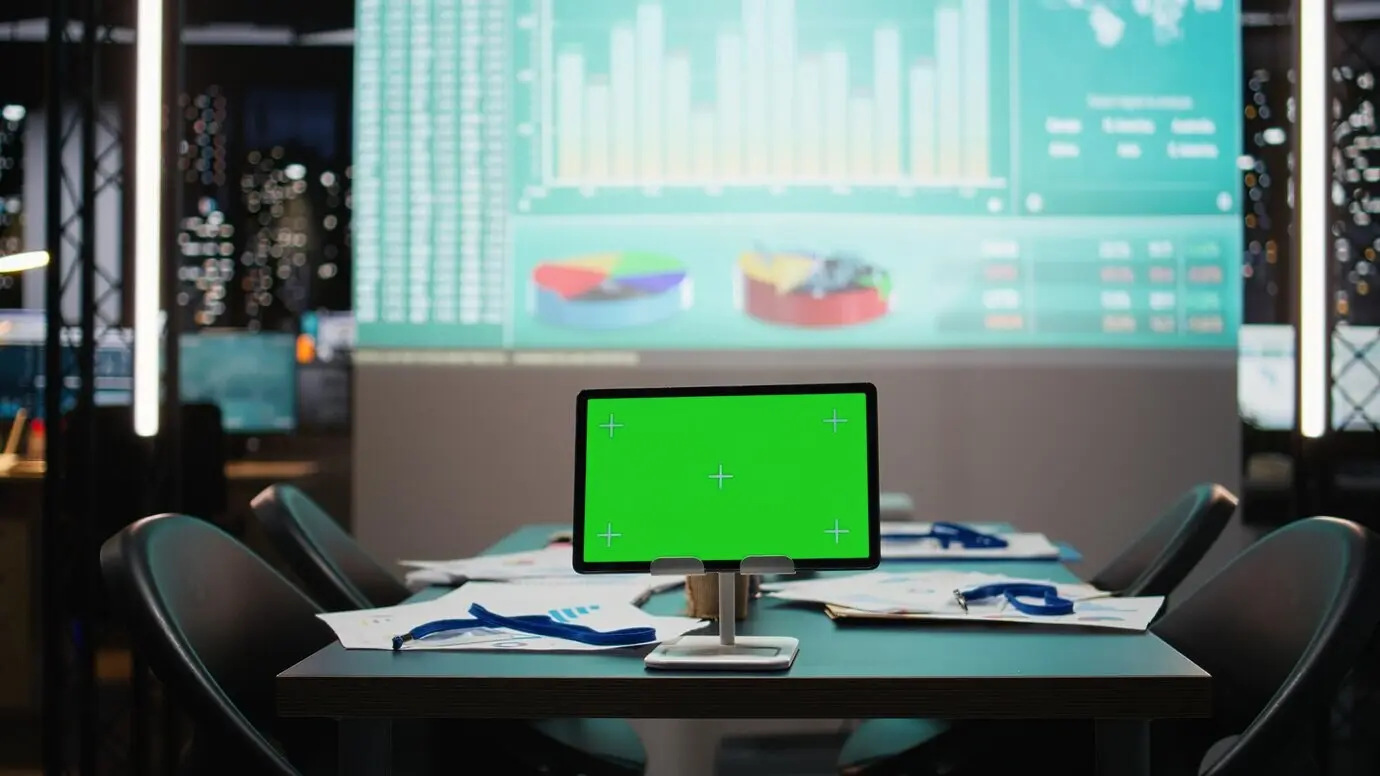 Tisch im Vorstandszimmer mit einem Tablet, auf dem ein isoliertes Mockup ausgeführt wird, unter nächtlicher Beleuchtung, Leistungsprojektionen und